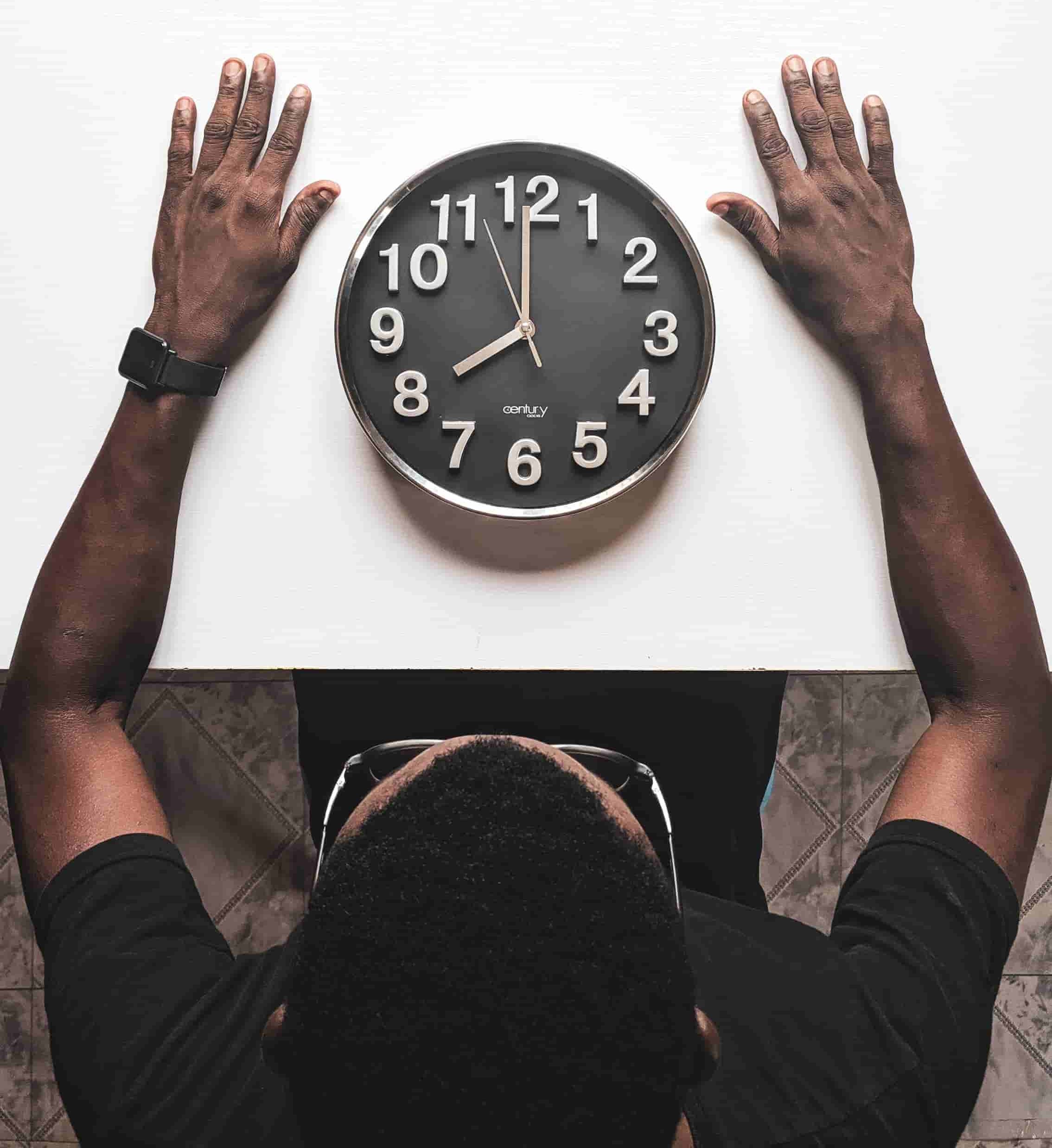 Picture of a man sat at a table looking at a clock